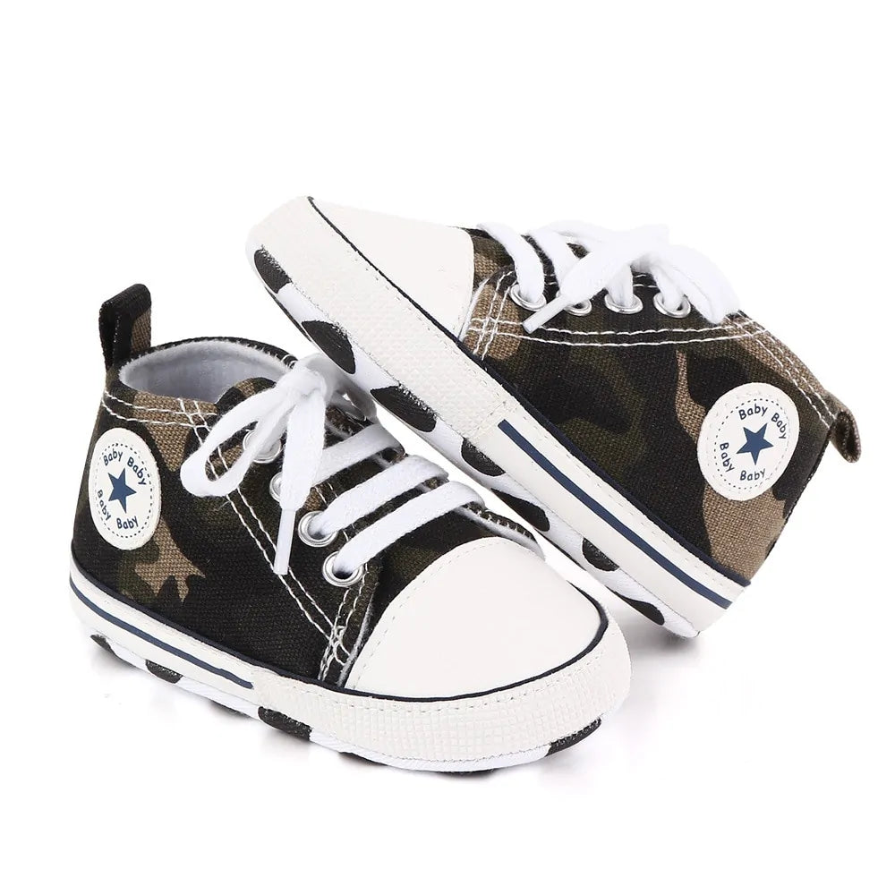 Pair of baby shoes with camouflage pattern and white laces on a white background
