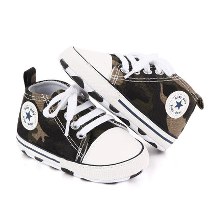 Pair of baby shoes with camouflage pattern and white laces on a white background